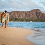 Couple walk along Waikiki with Leahi in back