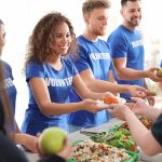 Volunteers serving food to poor people indoors